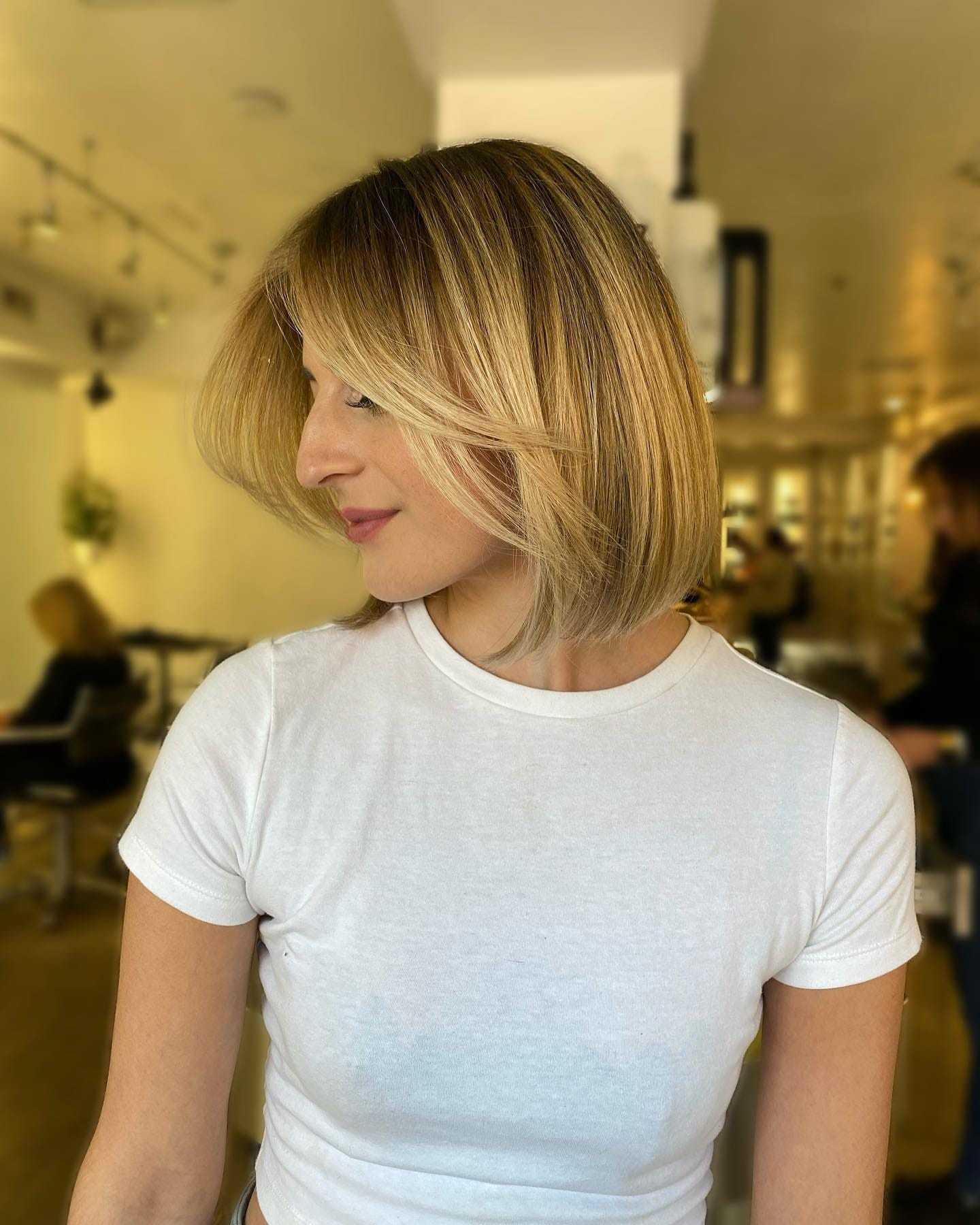 Blonde woman with a fresh, stylish bob haircut in a salon setting.